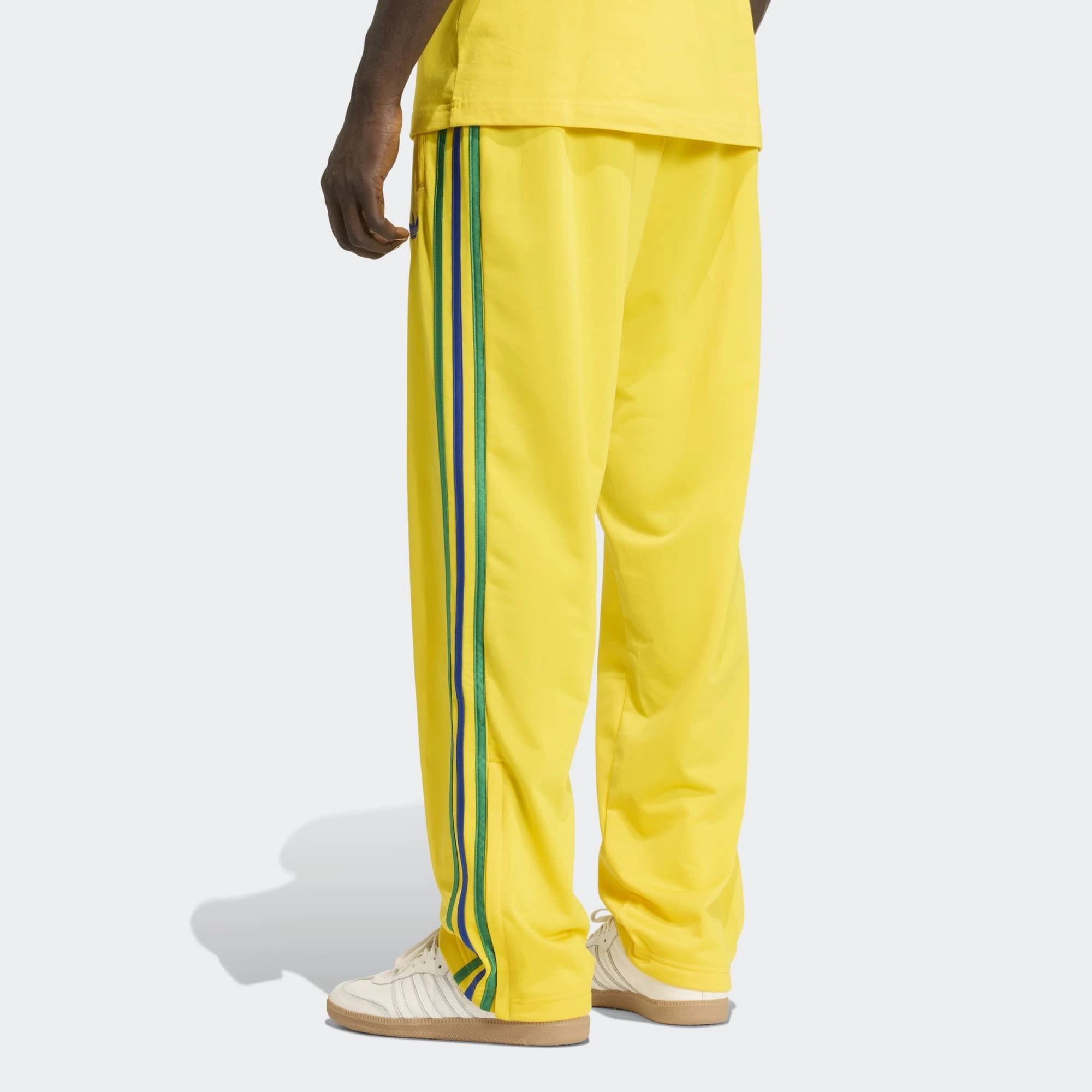 „Gelbe adidas Originals Firebird Track Pants (KD8340) mit grünen Streifen und Details in Collegiate Royal Blau – bunte Retro-Trainingshose erhältlich bei Stickabush Berlin.“