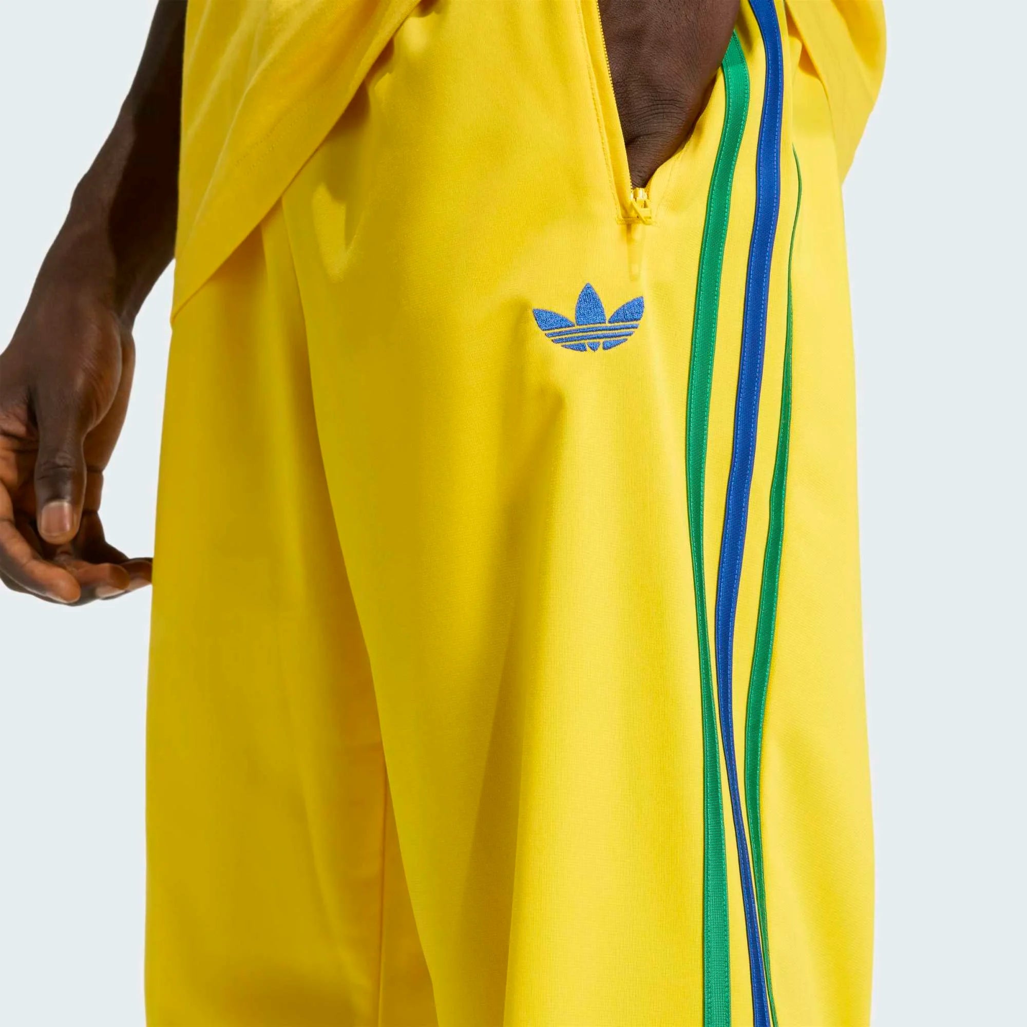 „Gelbe adidas Originals Firebird Track Pants (KD8340) mit grünen Streifen und Details in Collegiate Royal Blau – bunte Retro-Trainingshose erhältlich bei Stickabush Berlin.“