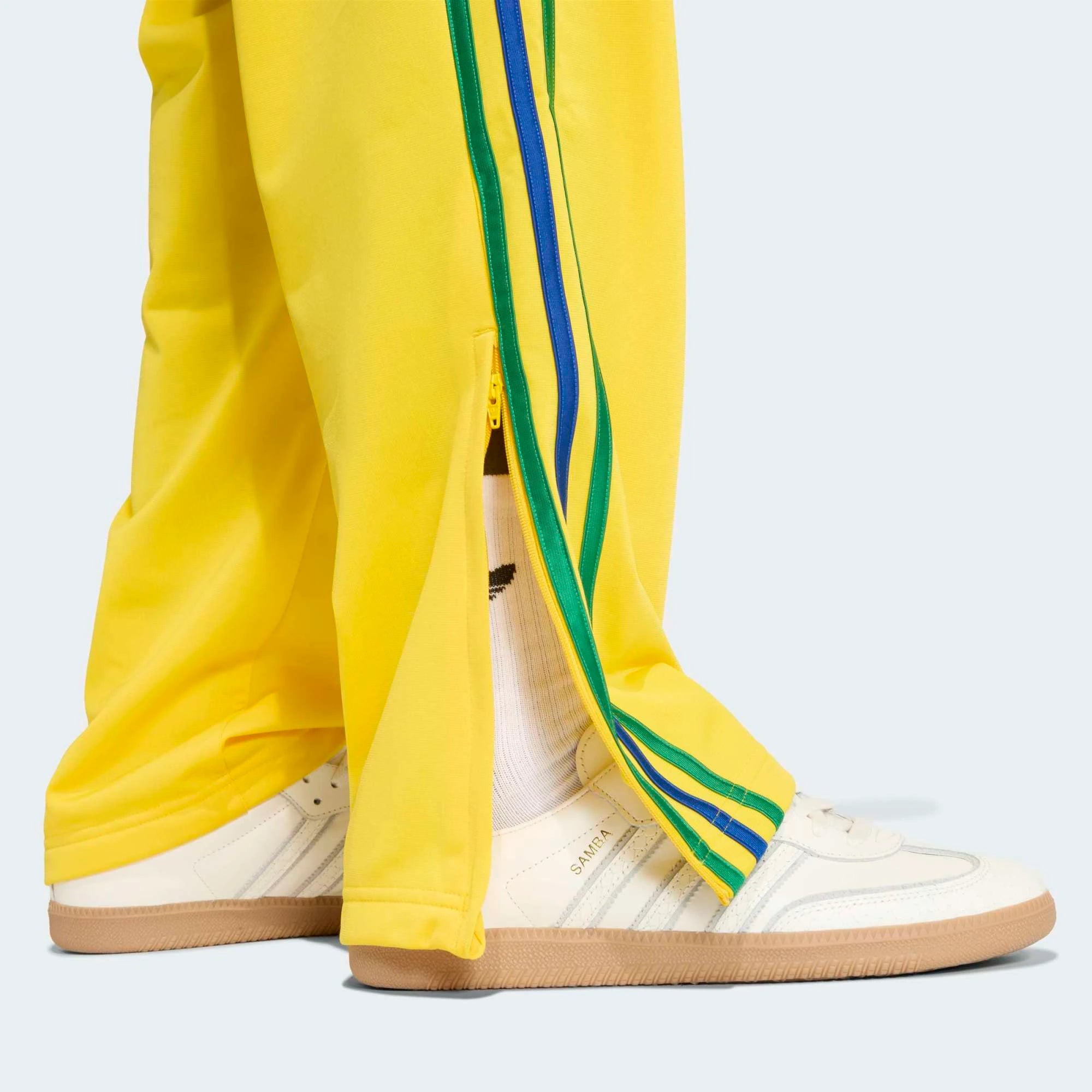 „Gelbe adidas Originals Firebird Track Pants (KD8340) mit grünen Streifen und Details in Collegiate Royal Blau – bunte Retro-Trainingshose erhältlich bei Stickabush Berlin.“