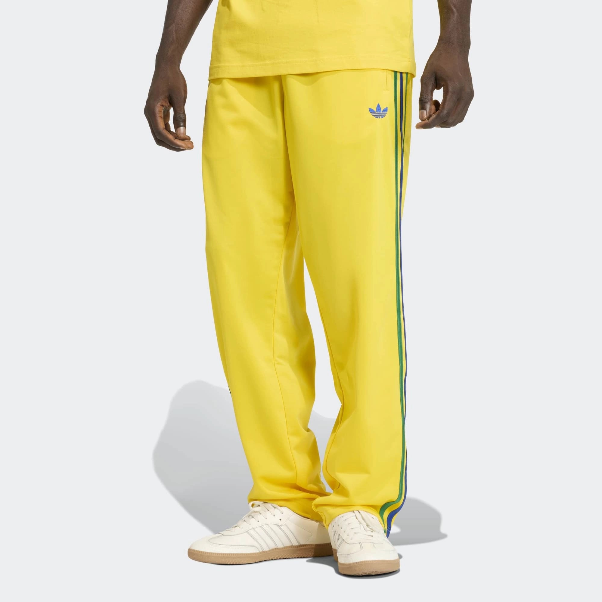 „Gelbe adidas Originals Firebird Track Pants (KD8340) mit grünen Streifen und Details in Collegiate Royal Blau – bunte Retro-Trainingshose erhältlich bei Stickabush Berlin.“