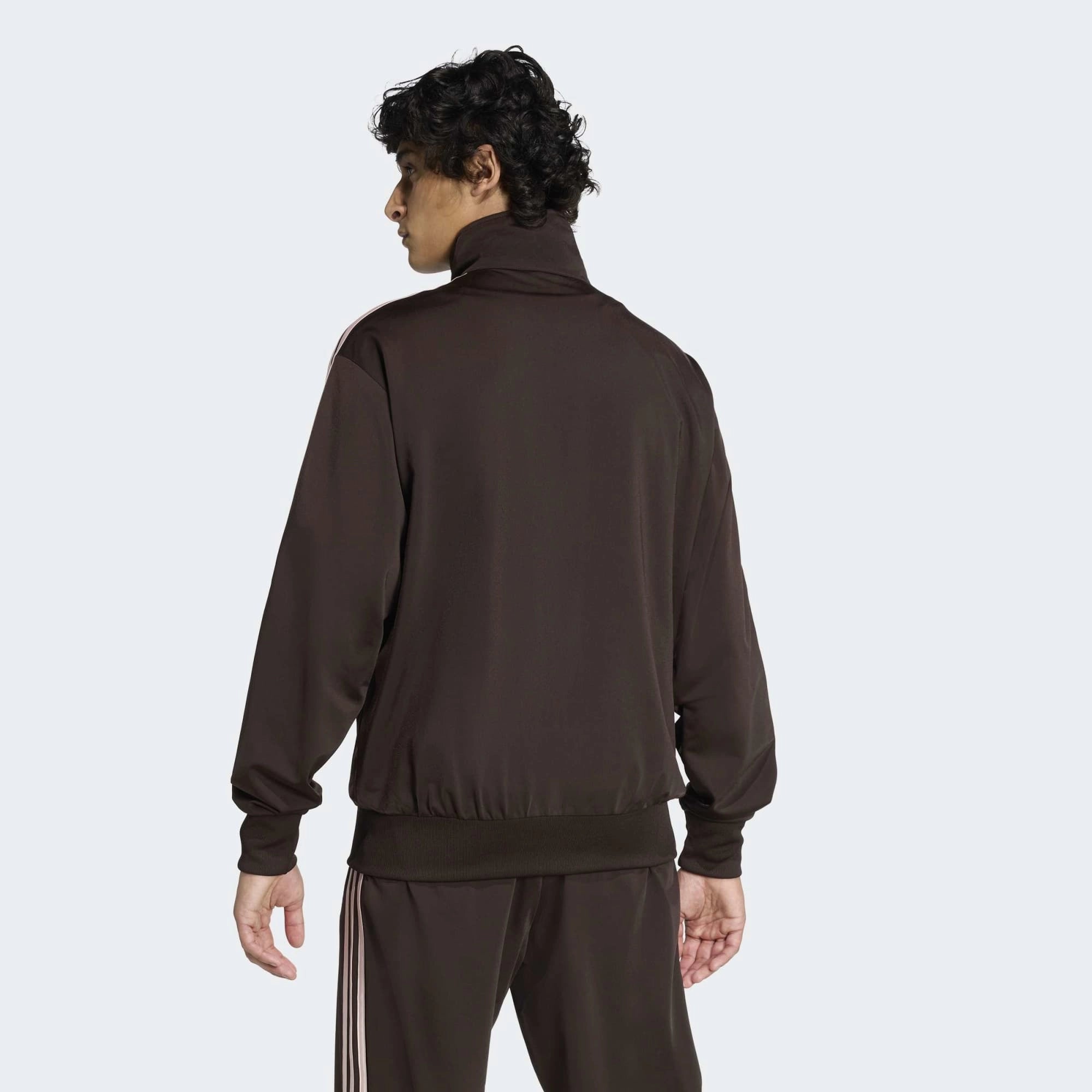 “Die braune adidas Originals Firebird Trainingsjacke in Aurora Coffee mit altrosa farbenen 3-Streifen und Stehkragen im Retro-Look bei Stickabush“.