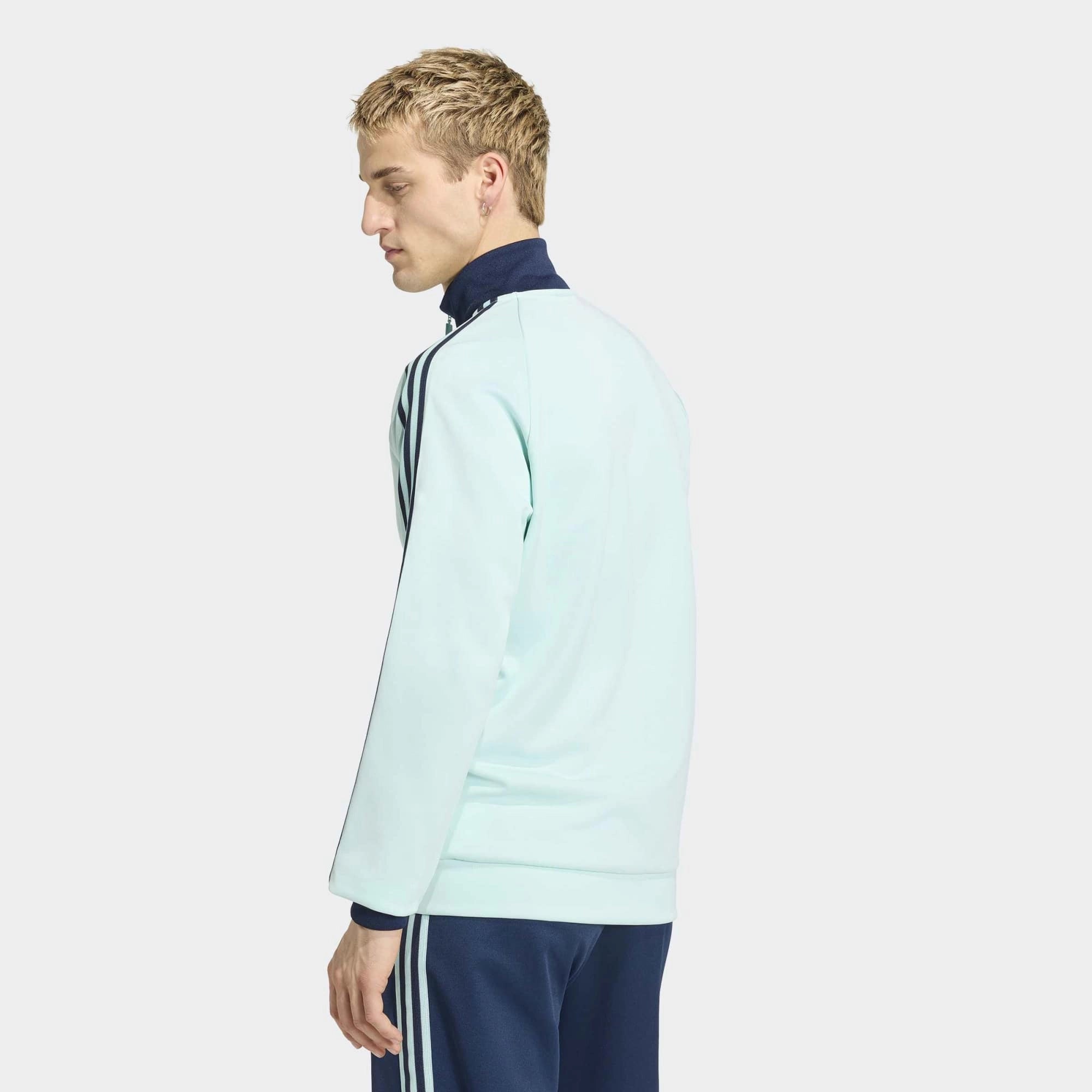 “Die türkise adidas Originals Deutschland OG Trainingsjacke (Semi Flash Aqua) mit klassischen weißen 3-Streifen und Retro-Details bei Stickabush“.