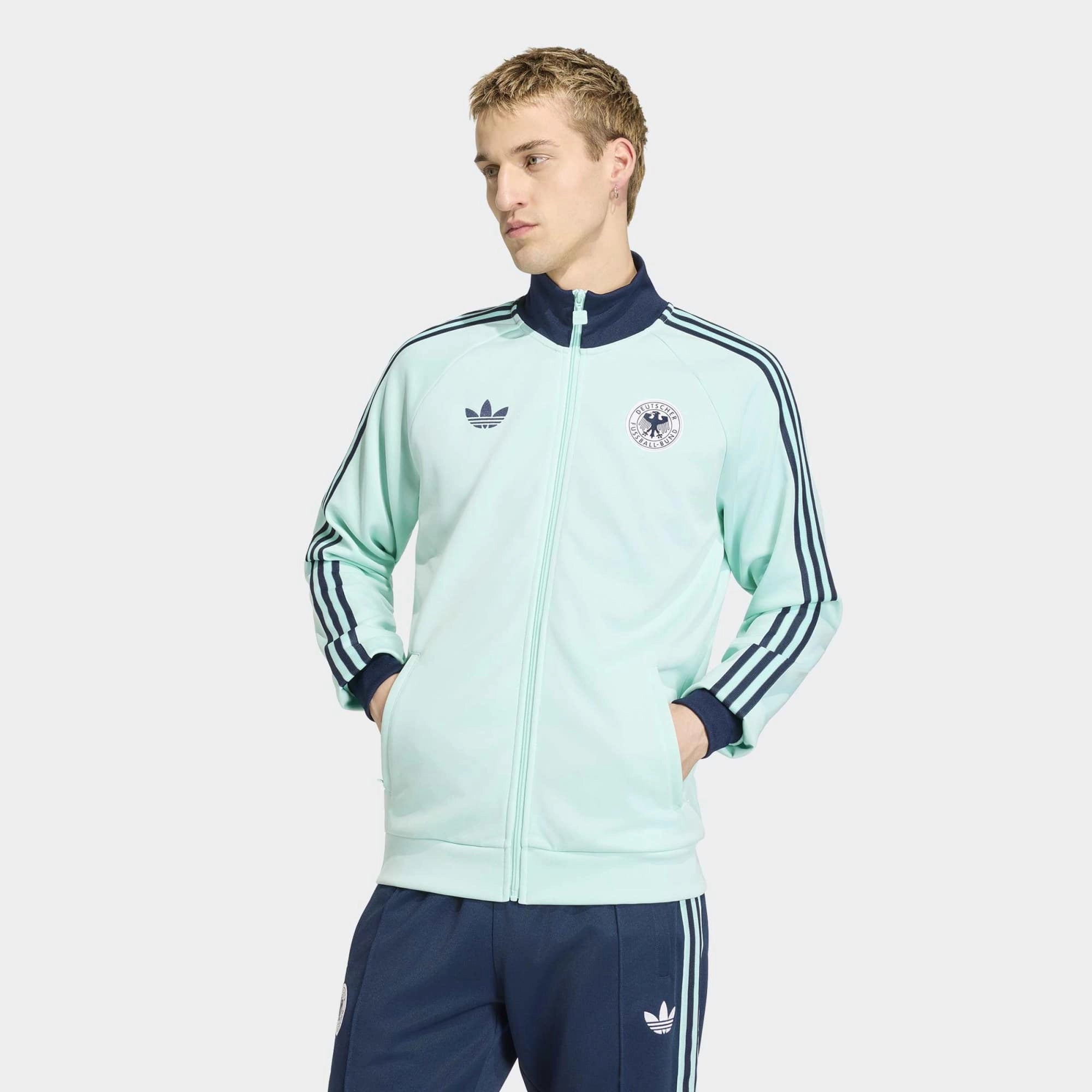 “Die türkise adidas Originals Deutschland OG Trainingsjacke (Semi Flash Aqua) mit klassischen weißen 3-Streifen und Retro-Details bei Stickabush“.