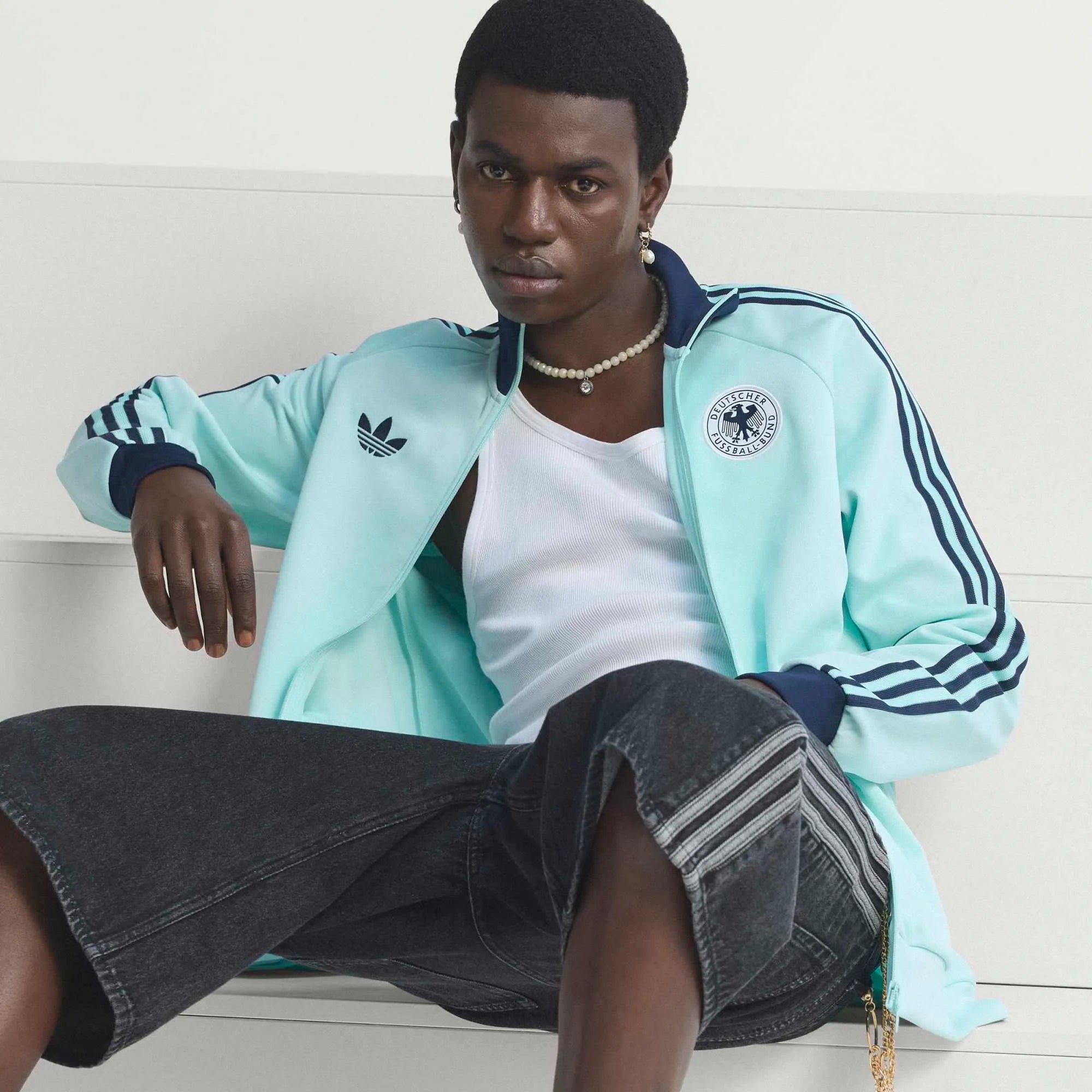 “Die türkise adidas Originals Deutschland OG Trainingsjacke (Semi Flash Aqua) mit klassischen weißen 3-Streifen und Retro-Details bei Stickabush“.