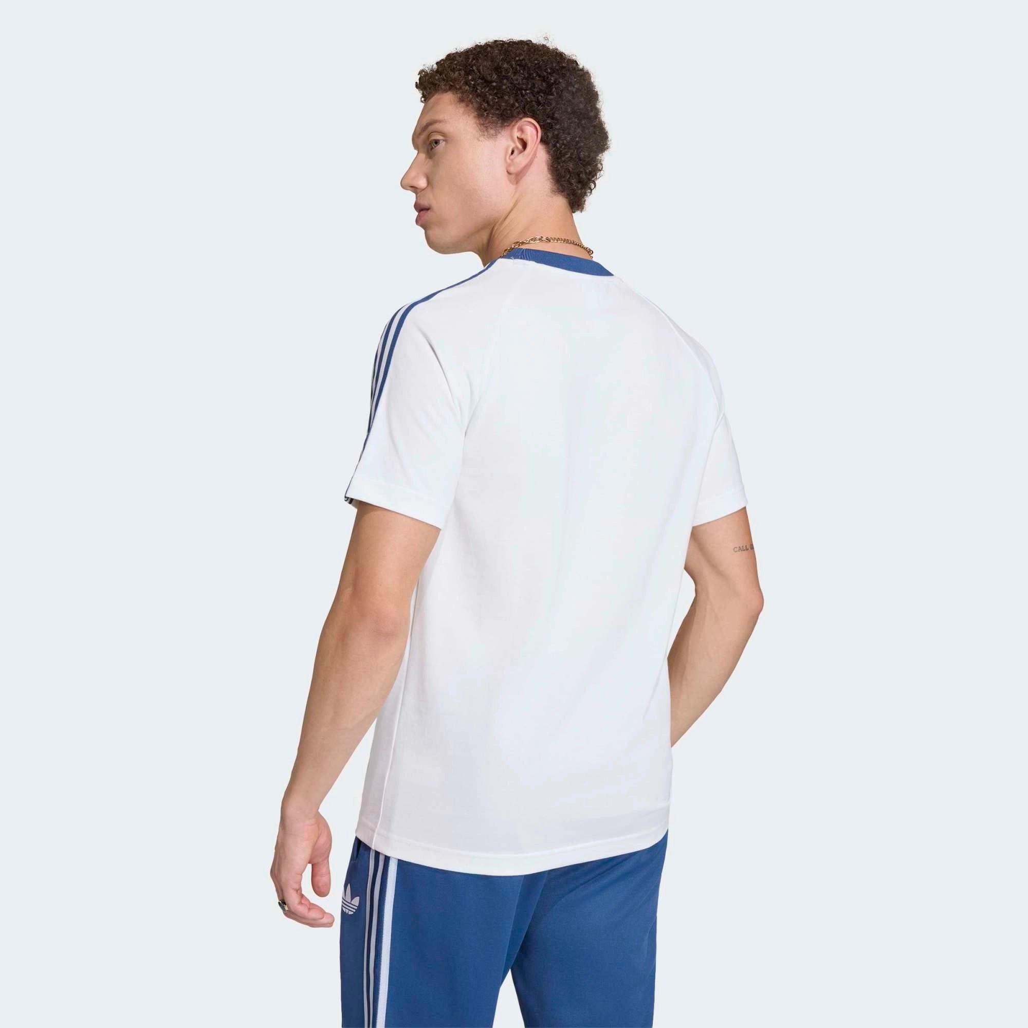 “adidas Originals Italien OG T-Shirts in Crystal White (KC6611) mit den klassischen blauen Streifen auf den Schultern, dem Italien-Wappen und dem blauen Trefoil-Logo auf der Brust bei Stickabush Berlin.“
