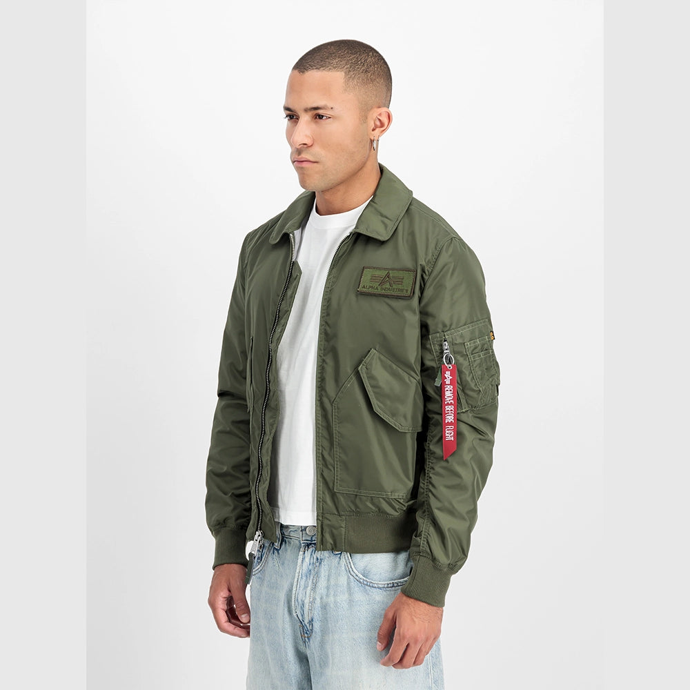 Alpha Industries CWU-36/P TT Light Bomberjacke in Dark Olive (266101-142) mit „Remove Before Flight“ Tag bei Stickabush Berlin.
