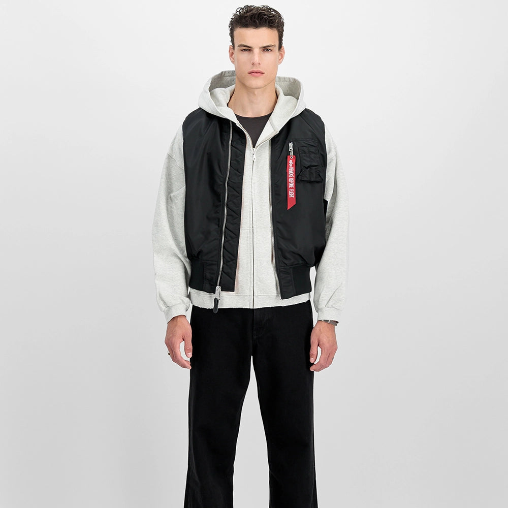 Schwarze Alpha Industries MA-1 Vest Heritage für Herren mit dem ikonischen roten Remove Before Flight Tag und orangenem Innenfutter bei Stickabush Berlin.
