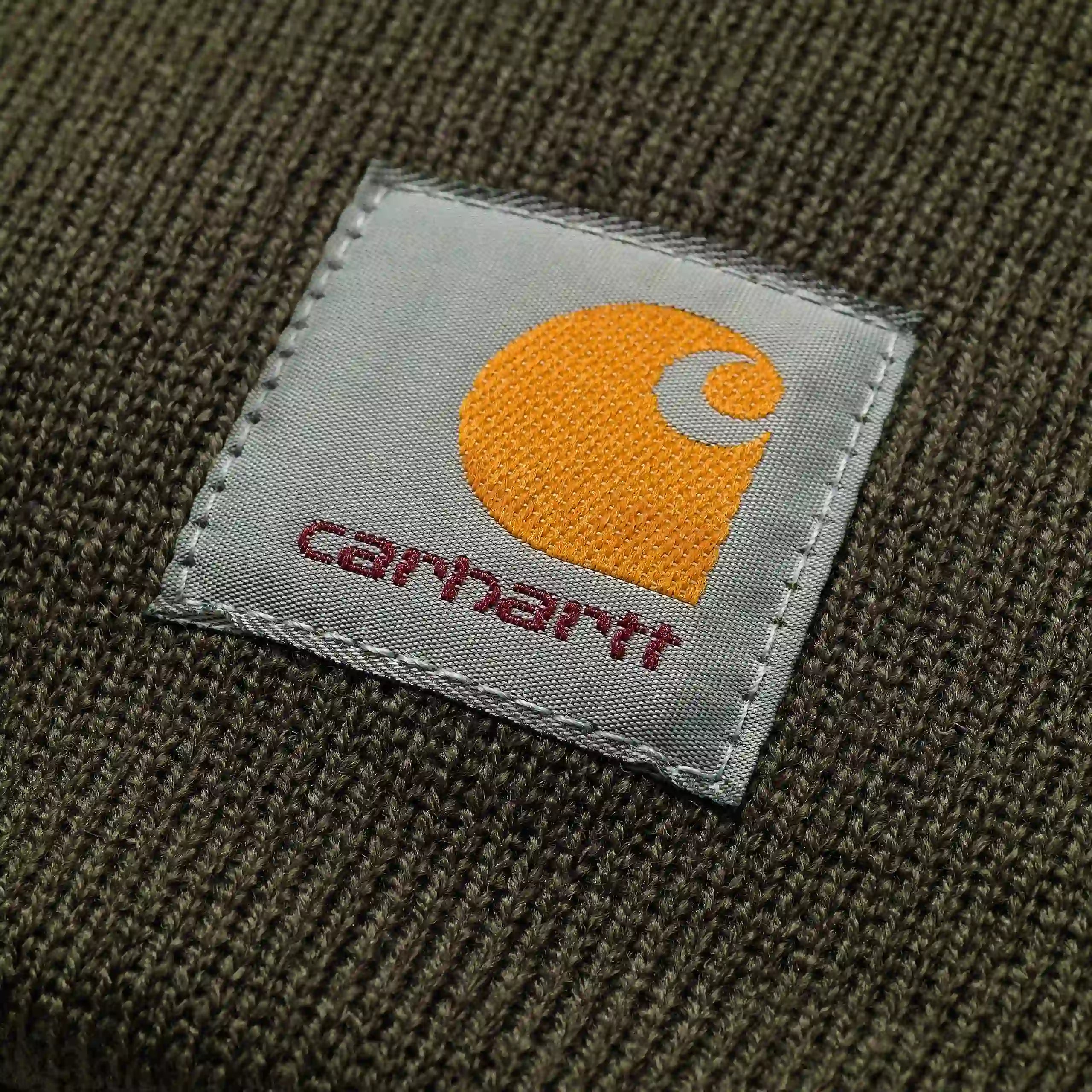"Dunkelgrüne Carhartt WIP Strickmütze aus Acryl. Klassischer Rippstrick, umschlagbarer Saum mit gewebtem Carhartt Logo-Patch."