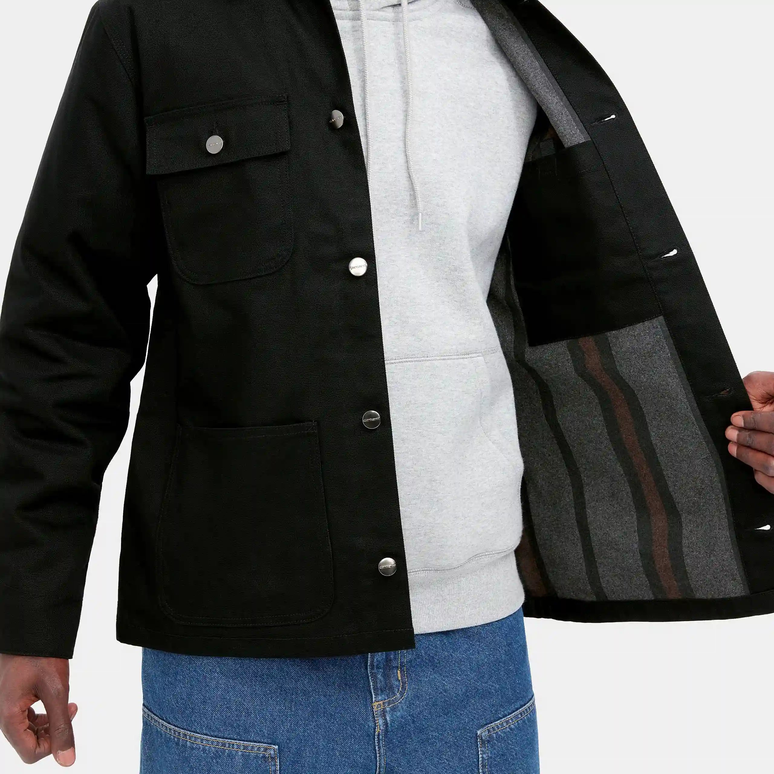 “Schwarzer ("rigid") Carhartt WIP Michigan Coat (Winter). Robuste Winterjacke aus ungefärbtem Baumwoll-Canvas, mit Steppfutter, Knopfverschluss und vier aufgesetzten Taschen.“