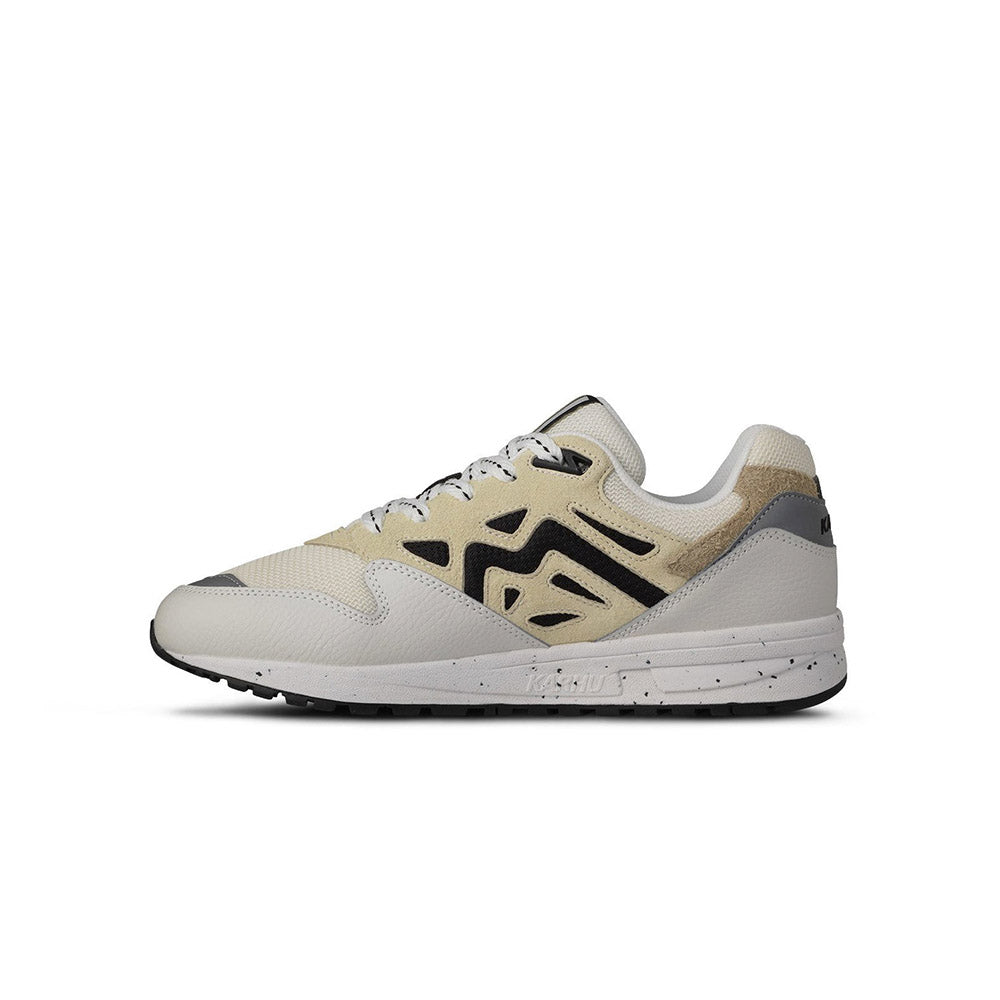 “Die Karhu Legacy 96 - Blanc de Blanc/Wood Ash, F806084, Sneakers präsentieren sich in einem beigen und hellgrauen Design mit schwarzen Akzenten. Sie verfügen über weiße Schnürsenkel, eine klobige Sohle, einen perforierten Zehenbereich und einen strukturierten Absatz.“