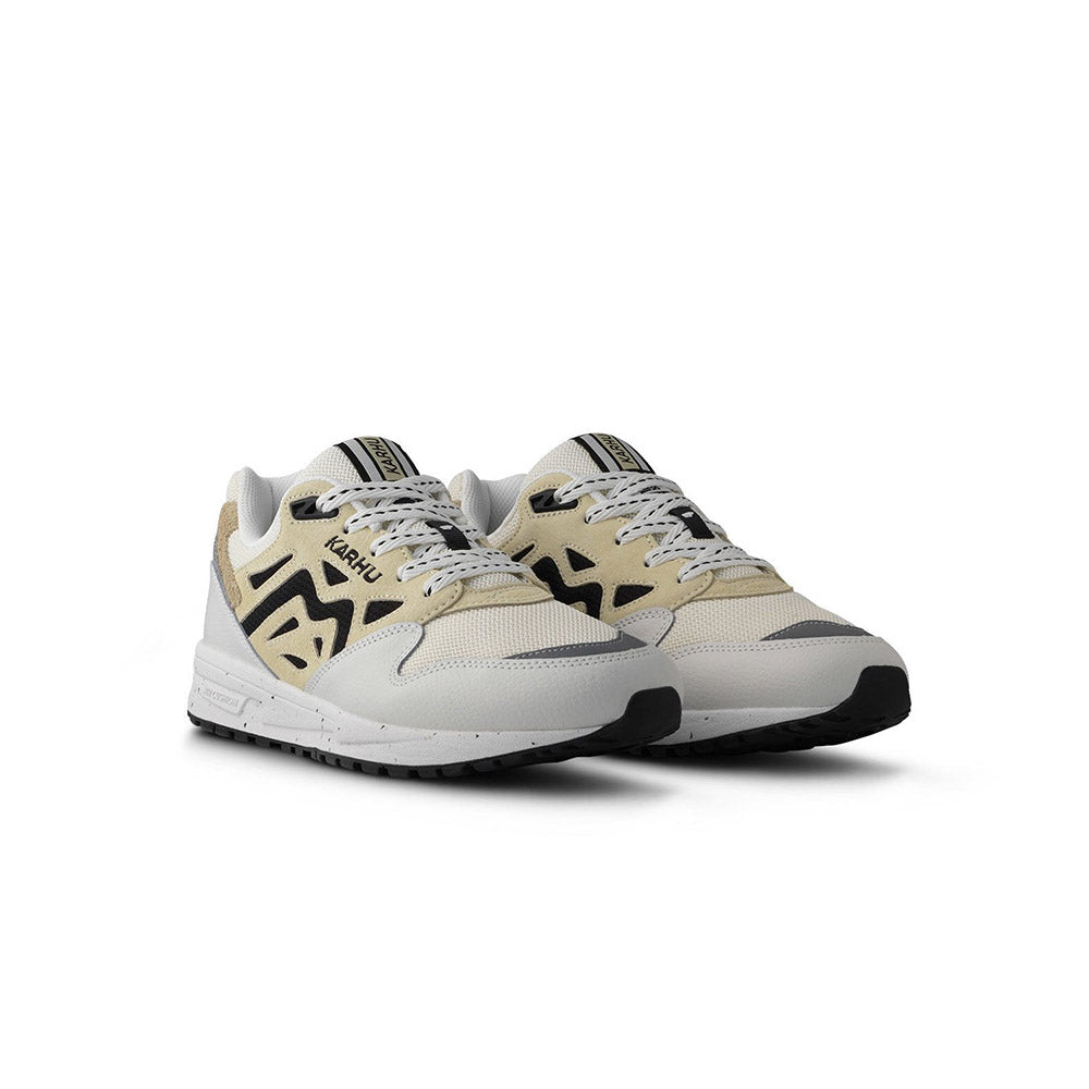 “Die Karhu Legacy 96 - Blanc de Blanc/Wood Ash, F806084, Sneakers präsentieren sich in einem beigen und hellgrauen Design mit schwarzen Akzenten. Sie verfügen über weiße Schnürsenkel, eine klobige Sohle, einen perforierten Zehenbereich und einen strukturierten Absatz.“