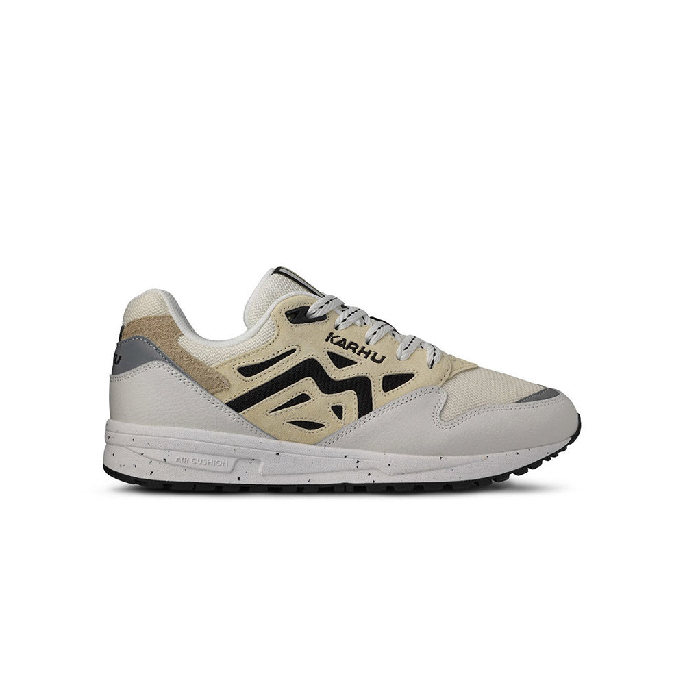 “Die Karhu Legacy 96 - Blanc de Blanc/Wood Ash, F806084, Sneakers präsentieren sich in einem beigen und hellgrauen Design mit schwarzen Akzenten. Sie verfügen über weiße Schnürsenkel, eine klobige Sohle, einen perforierten Zehenbereich und einen strukturierten Absatz.“