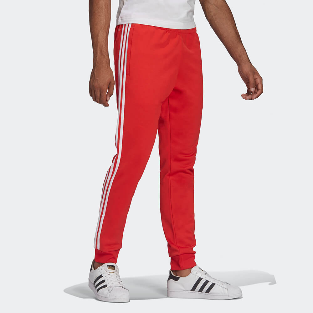 "Rote adidas Classics SST Track Pant mit weißen 3-Streifen und Trefoil-Logo, schmal zulaufendes Bein mit Rippbündchen bei Stickabush Berlin."