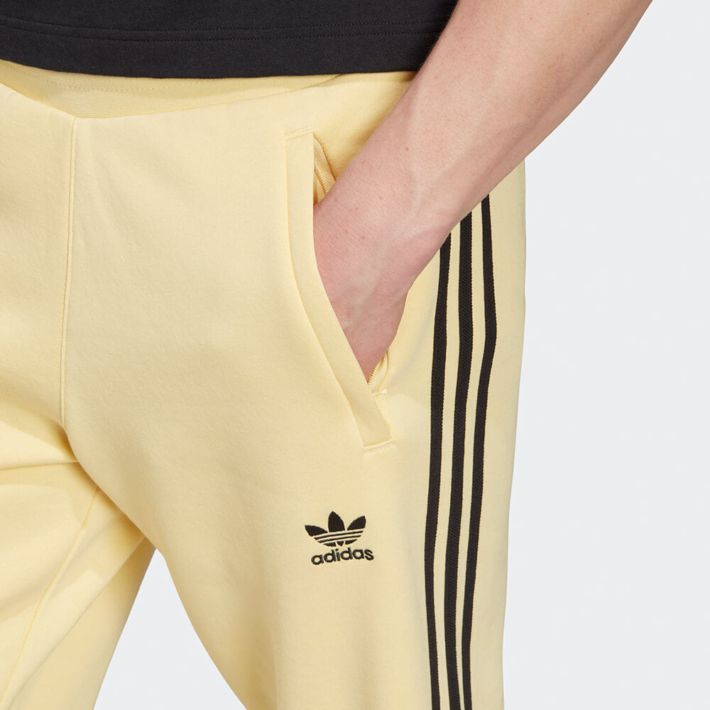 “Adidas Classics 3-Stripes Jogger – Yellow / Black. Gelbe Trainingshose aus weichem Stoff, mit schwarzen 3-Streifen und gesticktem Logo bei Stickabush Berlin."
