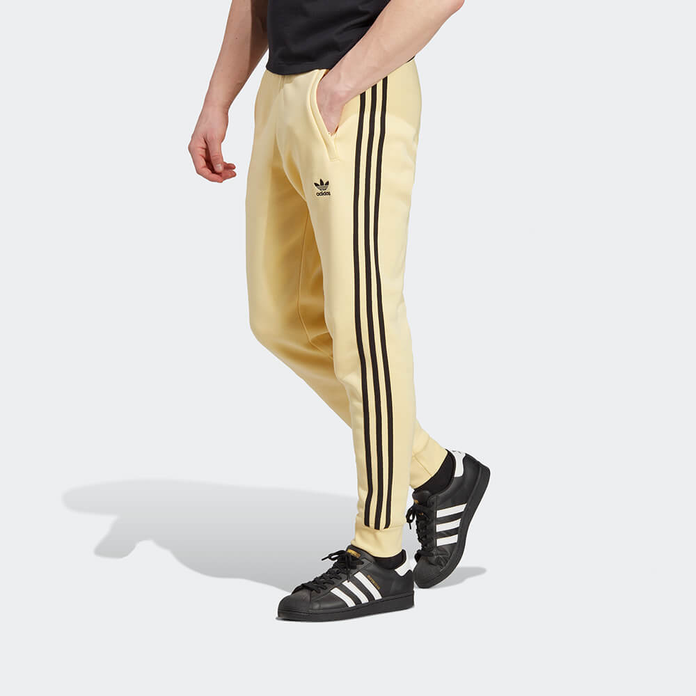 “Adidas Classics 3-Stripes Jogger – Yellow / Black. Gelbe Trainingshose aus weichem Stoff, mit schwarzen 3-Streifen und gesticktem Logo bei Stickabush Berlin."