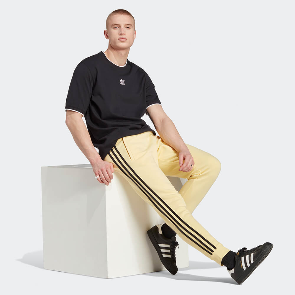 “Adidas Classics 3-Stripes Jogger – Yellow / Black. Gelbe Trainingshose aus weichem Stoff, mit schwarzen 3-Streifen und gesticktem Logo bei Stickabush Berlin."