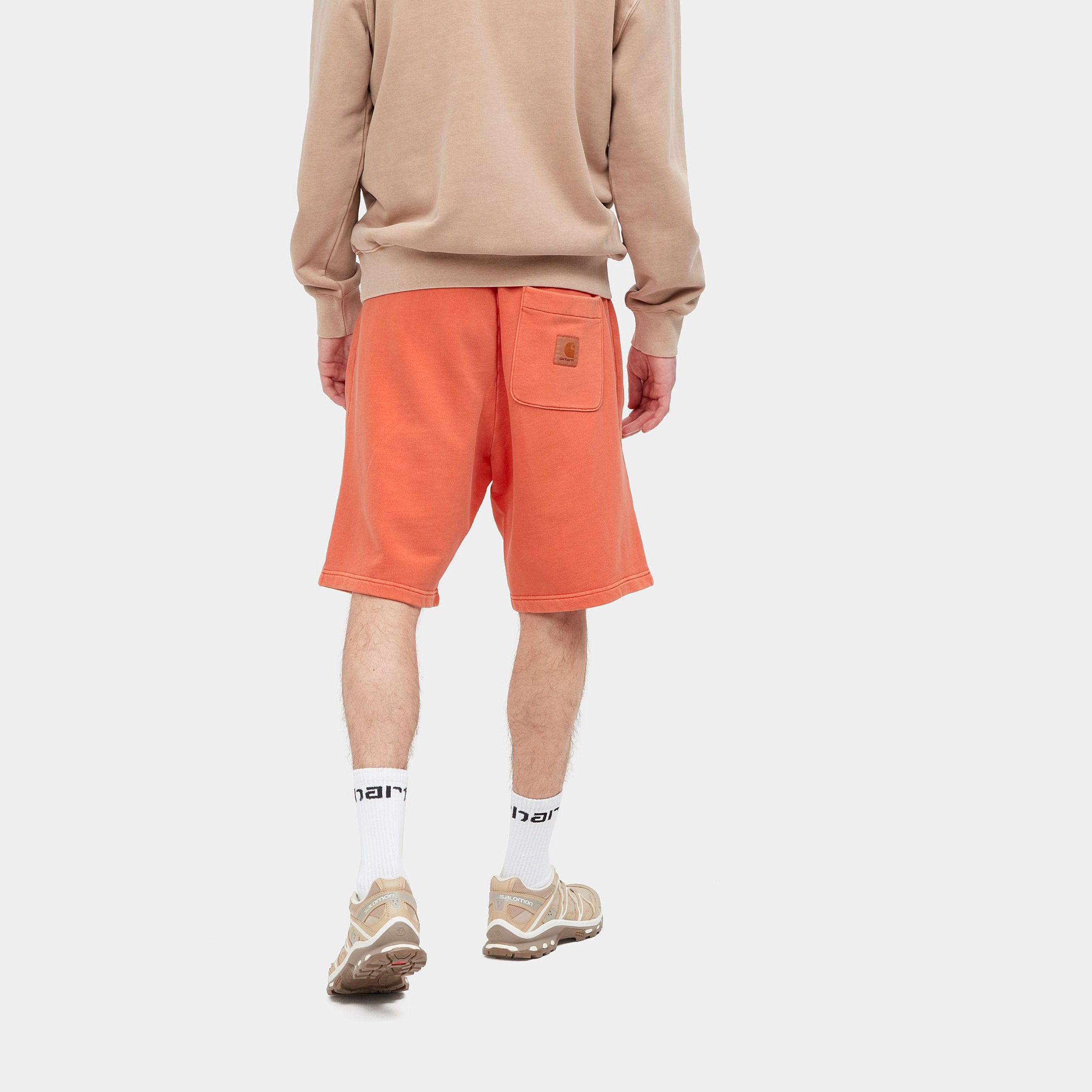 “Helles Orange ("Elba") Carhartt WIP Nelson Sweat Shorts. Kurze Herren-Sweathose aus weichem, stückgefärbtem Baumwolljersey. Lockere Passform, elastischer Bund mit Kordelzug, zwei Seitentaschen und eine Gesäßtasche mit kleinem, gewebtem Logo-Etikett. Bequeme Freizeithose für warme Tage.“