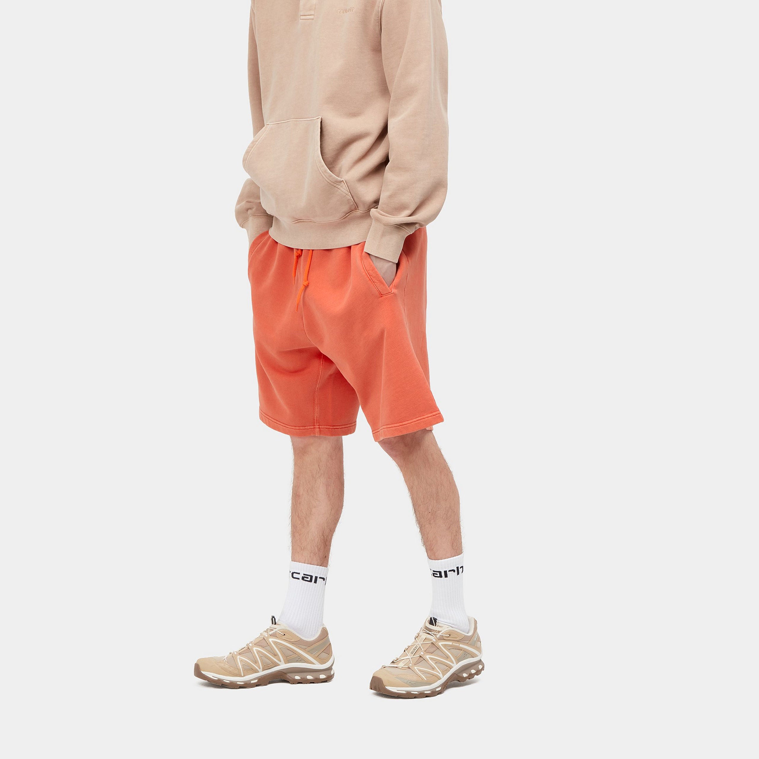 “Helles Orange ("Elba") Carhartt WIP Nelson Sweat Shorts. Kurze Herren-Sweathose aus weichem, stückgefärbtem Baumwolljersey. Lockere Passform, elastischer Bund mit Kordelzug, zwei Seitentaschen und eine Gesäßtasche mit kleinem, gewebtem Logo-Etikett. Bequeme Freizeithose für warme Tage.“